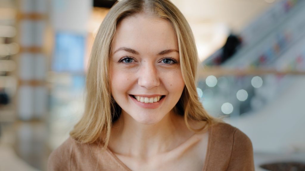 A young woman looks towards the camera and smiles. Aura Dental stands ready to help you whiten your smile today.